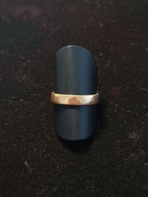 un gros plan d'une bague avec un anneau en or posée sur une surface noire