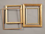 two gold picture frames hanging on a wall next to each other