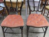 une paire de chaises peintes en noir avec des coussins d'assise rembourrés orange