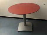 une table rouge avec un piètement en métal dans une pièce