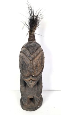 une image représentant une statue en bois surmontée d'une plume