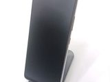 a black cell phone sitting on a stand on a white surface