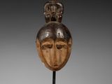 une sculpture en bois représentant la tête d'un homme surmontée d'un oiseau
