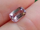 une personne tient un diamant rose dans la main, sur un fond vert