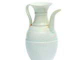 a white vase with a handle sitting on a table