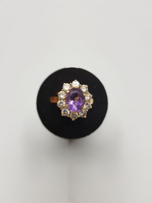 a close up of a ring with a purple stone surrounded by diamonds