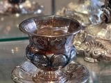 a glass cup and saucer sitting on a glass table