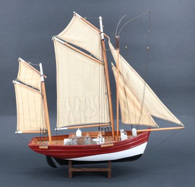 une maquette de voilier avec ses voiles, posée sur un socle