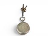 a silver pocket watch hanging from a chain on a white surface