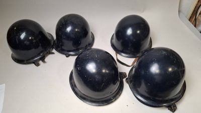 four black helmets are lined up on a white surface