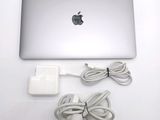 a silver apple laptop computer and a charger on a white table