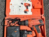 an orange box with a corded drill and a charger in it