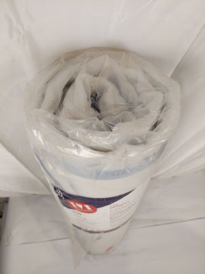 un rouleau de papier toilette emballé dans du plastique, posé sur un lit