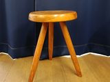 a small wooden stool sitting on the floor in front of a curtain