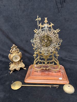 une horloge en or posée sur un socle en bois, à côté de deux autres horloges