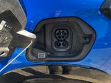a close up of a blue car with an electric charger plugged into it