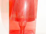 une lampe rouge posée sur une table transparente