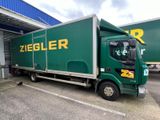 a large green truck parked in front of a building