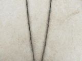 un vieux collier en argent orné d'un oiseau, posé sur un fond blanc