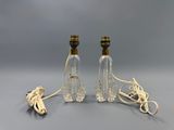deux lampes en verre transparent posées sur une surface grise, avec un cordon