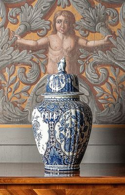 un vase bleu et blanc posé sur une étagère devant un tableau