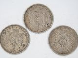 three silver coins sitting on top of a white surface