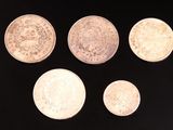 six types différents de pièces d'argent sur une surface noire