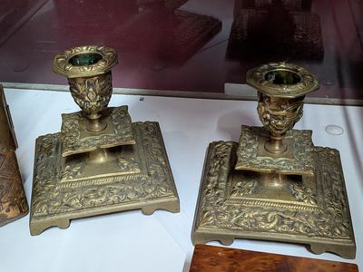 deux bougeoirs anciens en laiton exposés dans une vitrine