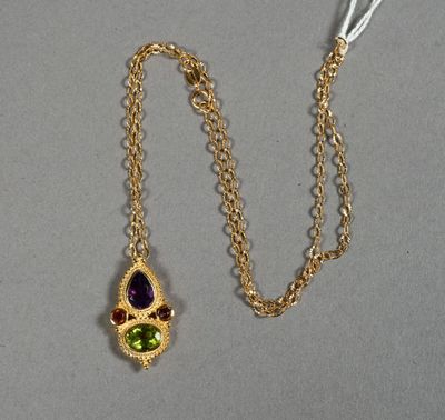 un gros plan sur une chaîne en or avec un pendentif vert et violet