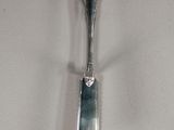 a silver spoon with a long handle hanging on a wall
