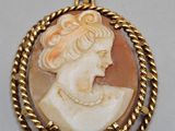 a gold and shell cameo pendant with a woman ' s face