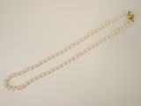 a close up of a pearl necklace on a white surface