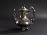an antique silver tea pot with a lid on a black background