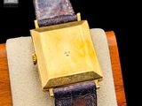 an image of a gold watch on a brown leather strap