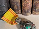 une médaille et un livre posés sur une table, à côté d'une rangée de livres