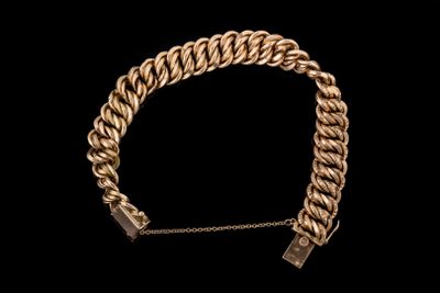 un bracelet en chaîne dorée muni d'un fermoir, sur fond noir