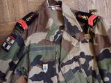 a camouflage jacket with patches on it on a wooden floor