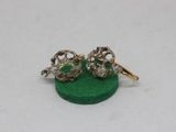 pair of gold and diamond skull earrings on a green base