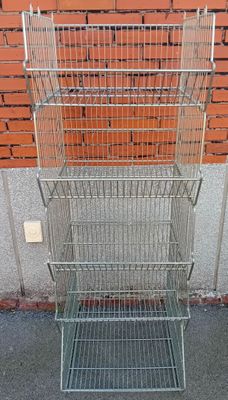 a metal rack with three baskets on it in front of a brick wall