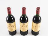 three bottles of red wine sitting next to each other on a white surface
