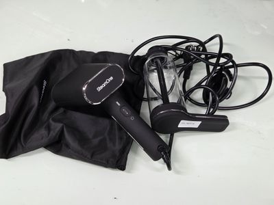 un sèche-cheveux noir et un parapluie noir posés sur une table blanche