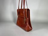 brown alligator skin handbag on white background
