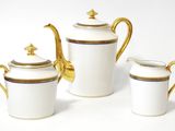 three pieces of white and gold tea set on a white surface