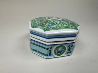 une petite boîte bleue et verte posée sur une table blanche