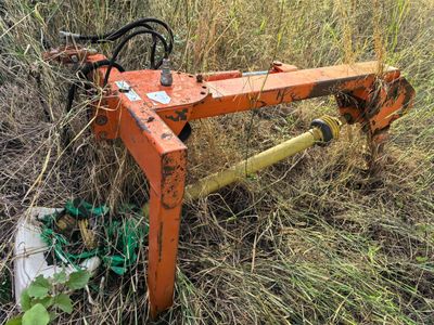 a rusted orange plow sitting in the grass