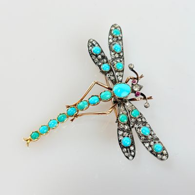 une photo d'une broche en forme de libellule, ornée de pierres turquoise et de diamants