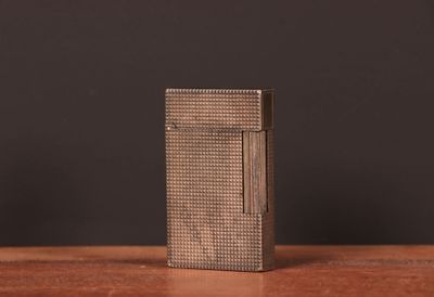 un vieux briquet posé sur une table en bois, près d'un mur noir
