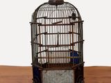 une cage à oiseaux avec un oiseau à l'intérieur, posée sur une table en bois