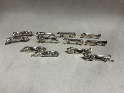 six silver plated dog figurines on a white surface