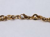 a close up of a gold chain bracelet on a white surface